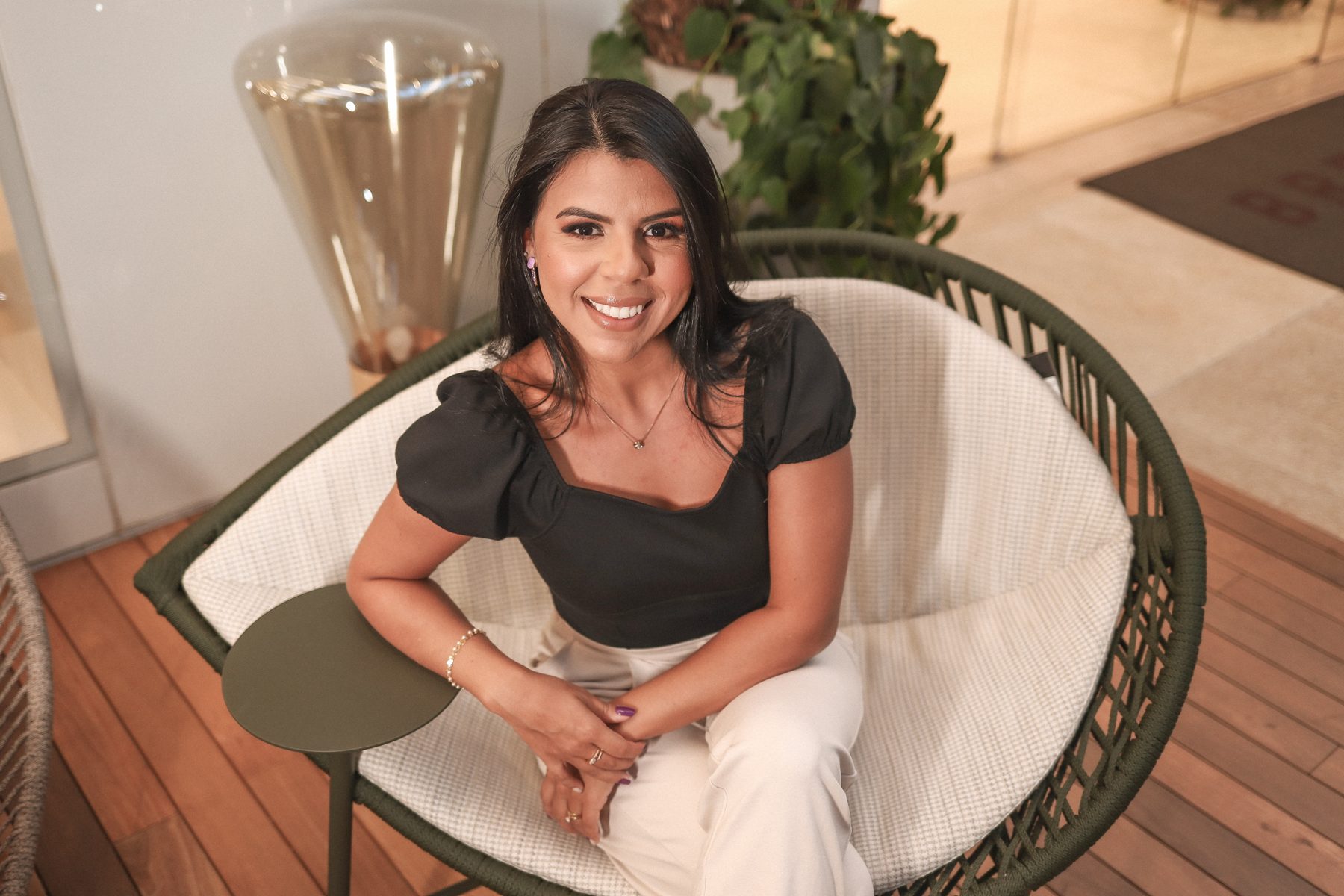 Thais Lasse sorrindo sentada em uma poltrona